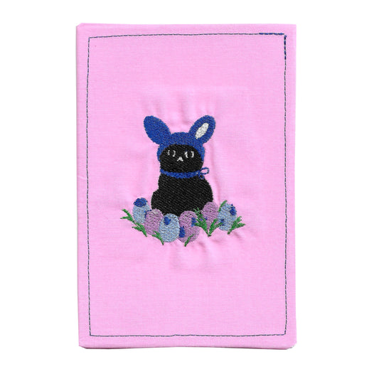 Pink fabric patch with a black cat and blue flowers design on a white background